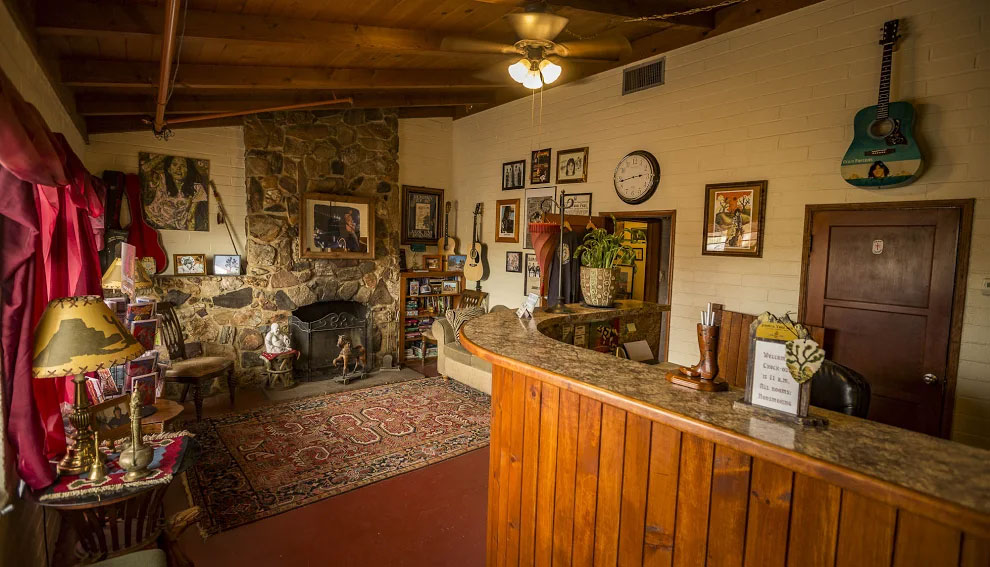 The main office, there is a tall wooden desk to the right and a seating area with a stone fire place to the left.